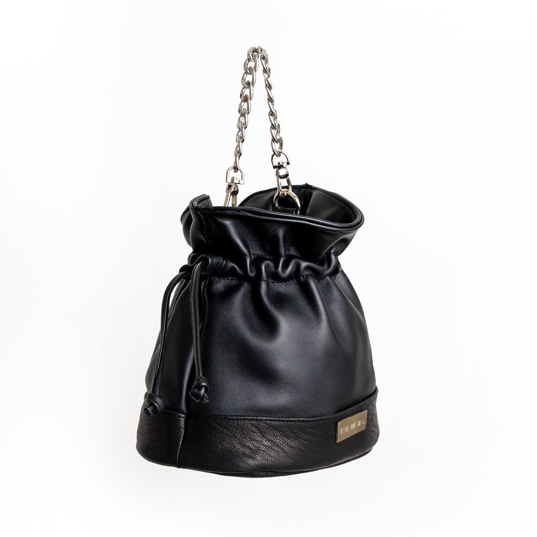 image of black bucket leather handbag, featuring two different lamb leathers, one very soft and one a more grainy leather. This image shows the bag with its chain strap and pulled tight with the drawstring. 